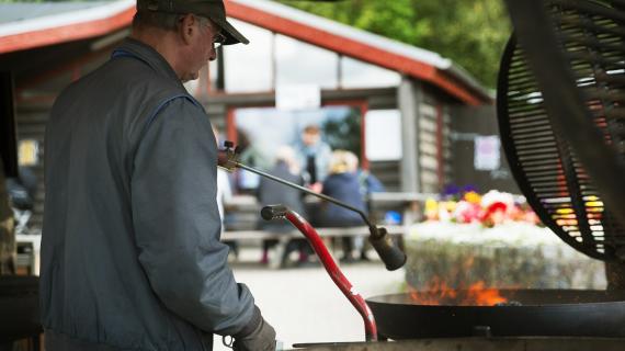 Mand griller på fællesgrill i Madsby Legepark